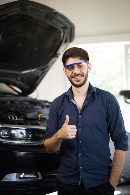 Portrait of caucasian bearded handsome man auto mechanic or manager in goggles smiling to camera