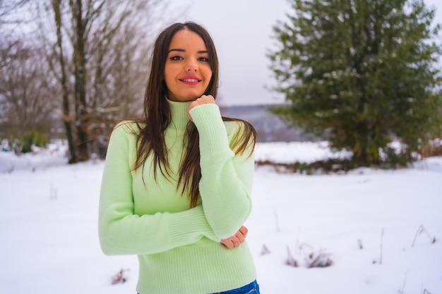 Portrait caucasian brunette with green outfit and woolen hat enjoying the snow