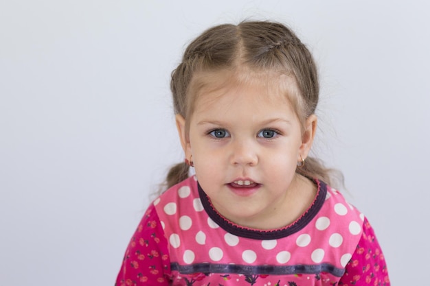 Portrait of caucasian child of three years old looking at camera with shiny eyes on the white background