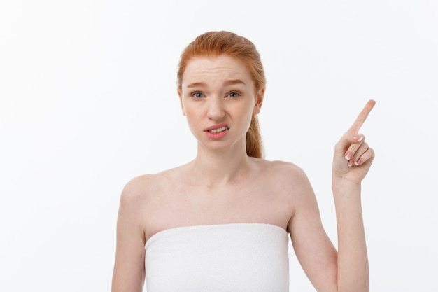 Portrait of caucasian cute in concern and shock, pointing index finger aside, over white background.