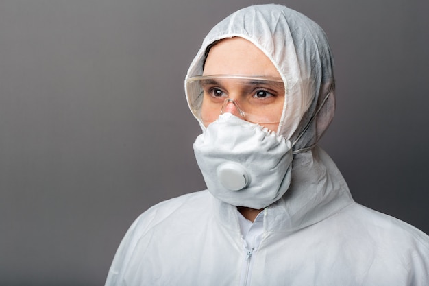 Portrait caucasian doctor in protective medical suit, biological hazard, medical mask FFP3,goggles. Doctor in chemical protection clothing for Coronavirus covid-19 disinfection.