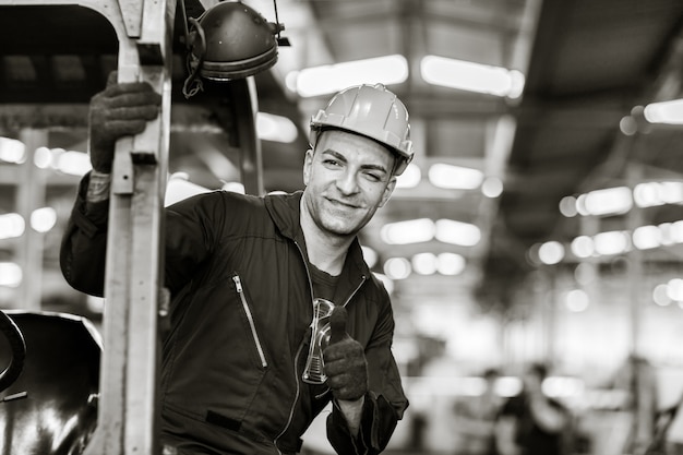 Ritratto dell'operaio caucasico bello astuto con i vestiti di sicurezza. fotografia in bianco e nero di arte industriale.