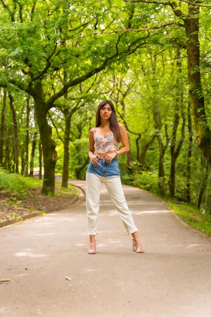 Ritratto di una ragazza caucasica su un sentiero in un parco cittadino posato alla moda in natura