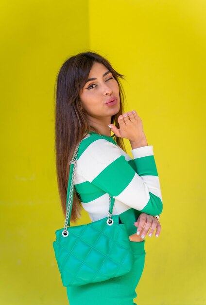 Portrait of a Caucasian girl in a white striped sweater on a green background blowing a kiss at the camera