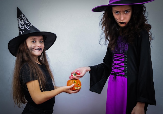 Portrait of a caucasian girl in a witch costume with a pumpkin and sweets