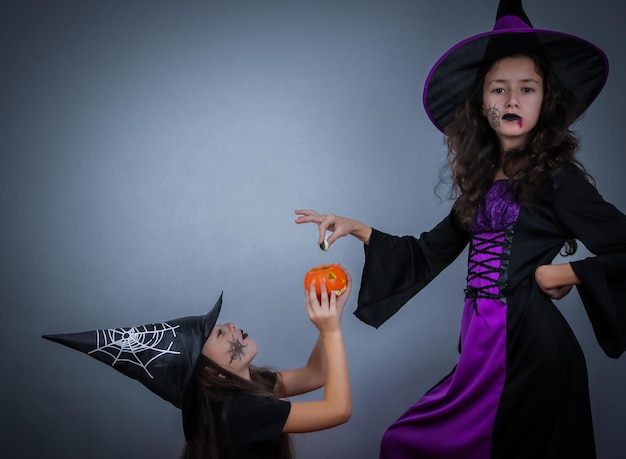 Portrait of a caucasian girl in a witch costume with a pumpkin and sweets