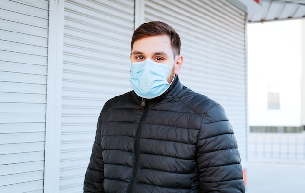 Portrait of caucasian man wearing Medical protective mask outdoors. Virus, coronavirus protection, air pollution, ecology, environmental awareness