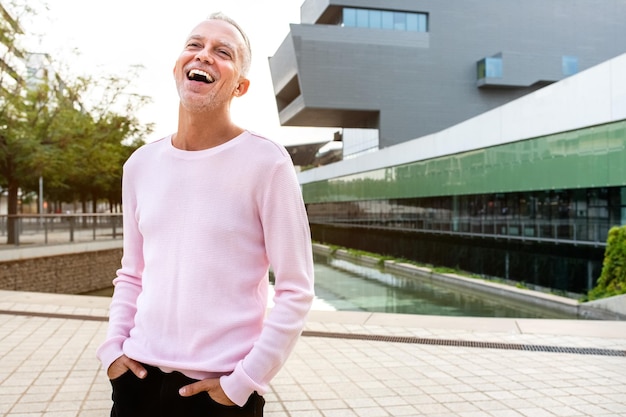 Portrait of caucasian man wearing pink sweater laughing on the street Copy space