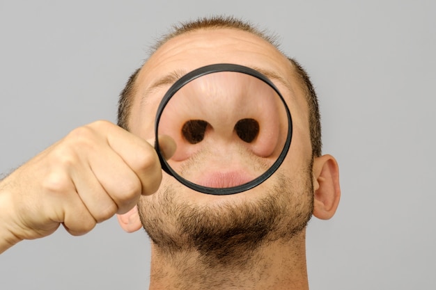 Portrait of caucasian man with magnifier makes fun face