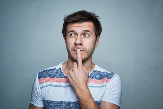 Portrait of caucasian man with think emotion on a gray background