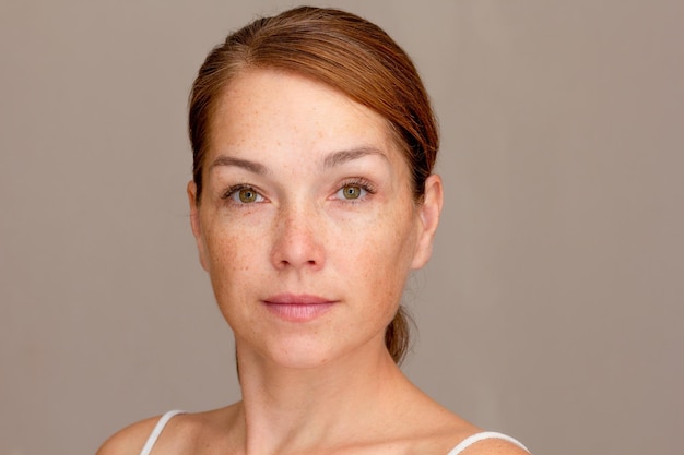 Portrait of caucasian middle aged woman of 40s looking at camera on gray background