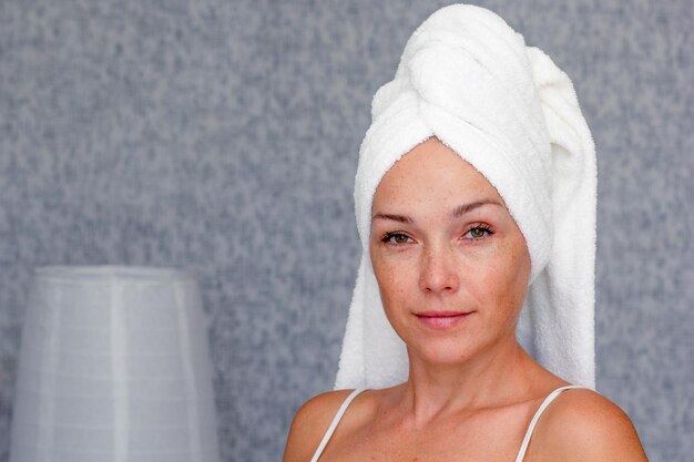 Portrait of caucasian middle aged woman of 40s with towel on head looking at camera