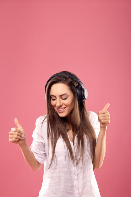 Портрет кавказской красивой женщины, слушающей музыку с помощью беспроводных наушников