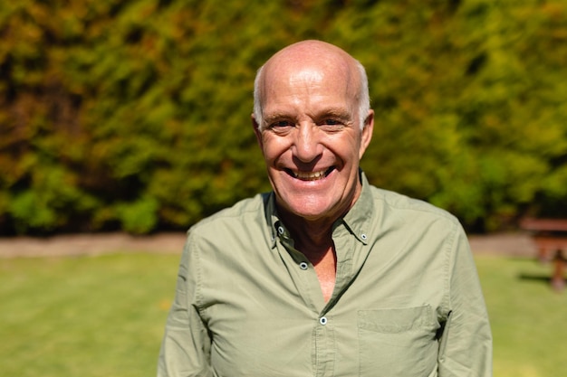 Photo portrait of caucasian senior man smiling while standing in the garden. people and emotions concept, unaltered.