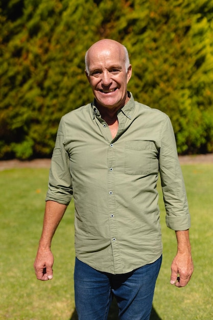Photo portrait of caucasian senior man smiling while standing in garden. people and emotions concept, unaltered.