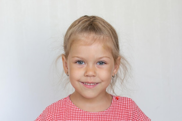 Портрет кавказской улыбающейся милой девочки пяти лет на сером фоне, смотрящей в камеру