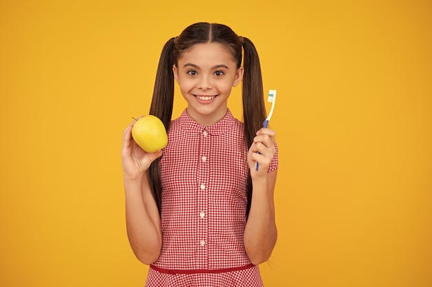 Portrait of caucasian teen girl holds a toothbrush brushing her teeth morning routine dental hygiene isolated on yellow background Happy teenager positive and smiling emotions of teen girl