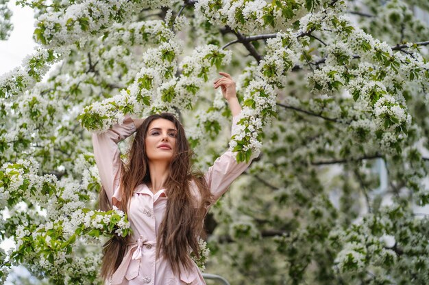 portrait of caucasian white woman with long hair in spring romantic nature park around bloom trees