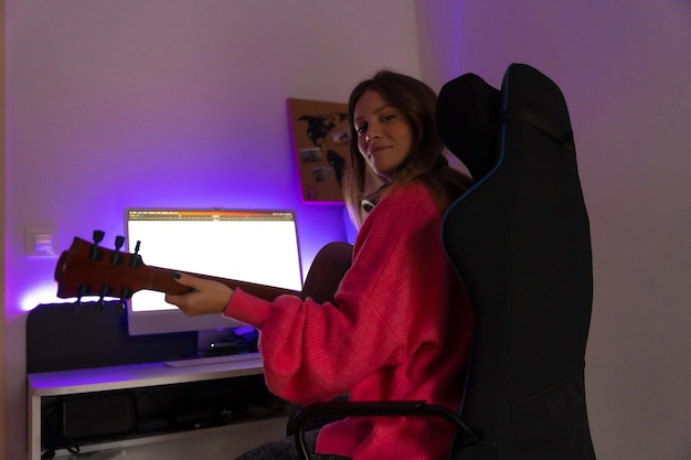 Portrait of caucasian woman learning to play guitar with online\
classes on computer