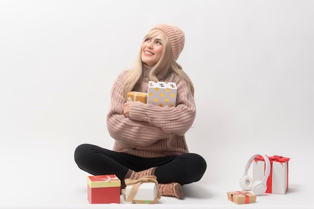 Portrait of Caucasian young woman wearing sweater holding gifts box over white background