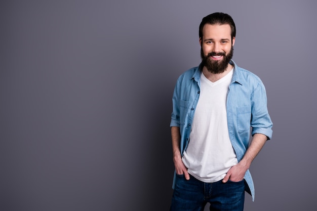 Portrait of charismatic enthusiastic guy relax rest free spring time put hands pockets wear stylish clothes isolated over grey color wall