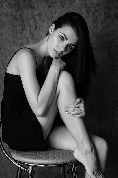 Portrait of a charismatic young brunette woman in a dress sitting on a chair