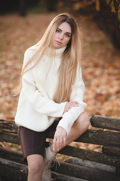 하얀 스웨터를 입은 멋진 미소를 가진 매력적인 금발 소녀의 초상화