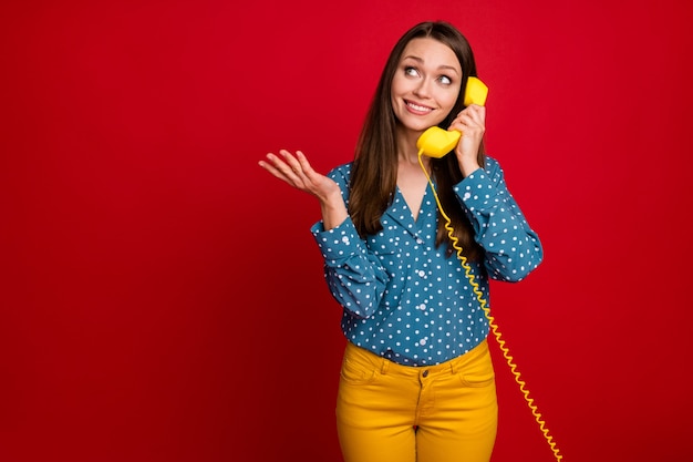 Portrait of charming cheerful cheery girl using receiver calling friend isolated over bright red color background