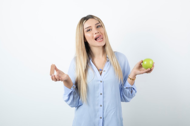 Ritratto di una ragazza affascinante che tiene mela verde sopra il muro bianco