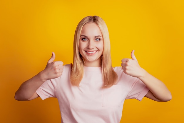 Portrait of charming lady beaming smile raise two thumbs up approve on yellow background