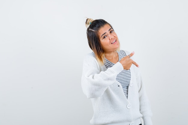 Portrait of charming lady pointing down in t-shirt, cardigan and looking proud