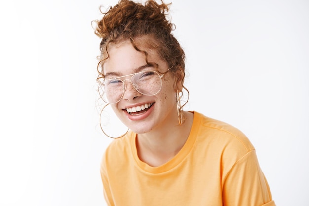 Portrait charming laughing happy young   redhead girl wearing glasses messy curly hairbun, grinning chuckling over comedy movie have hear fun hilarious joke.