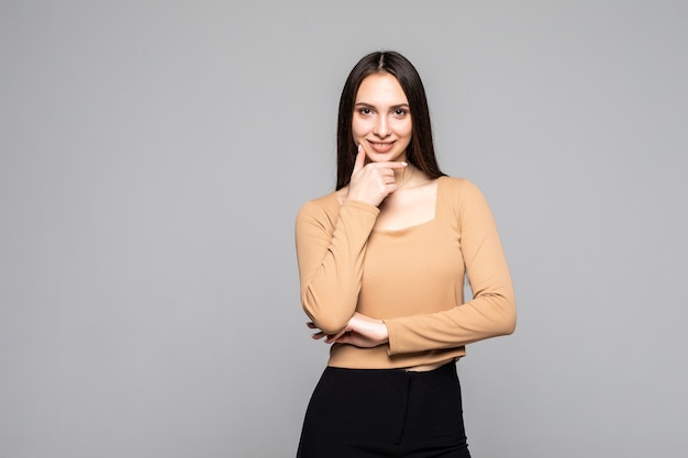 Portrait of charming and lovely young woman looks away keep her hand on the chin isolated on gray wall with copy space for text