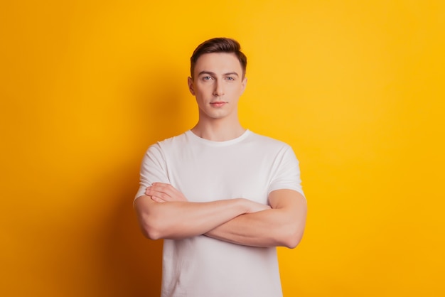 Portrait of charming self-assured guy look camera folded hands on yellow background