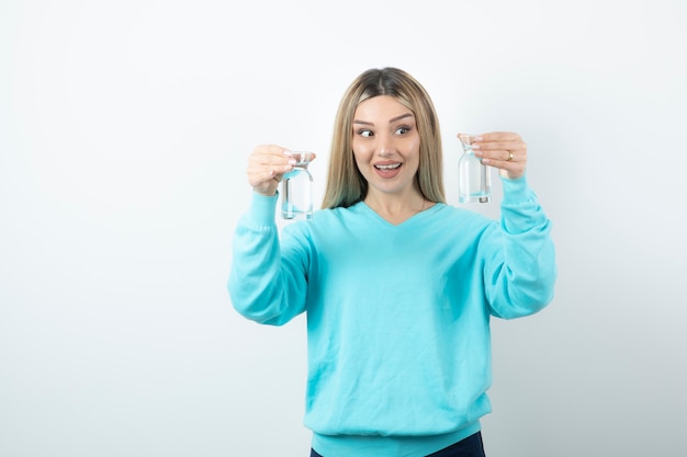 Portrait of charming woman holding two glass pitchers of water