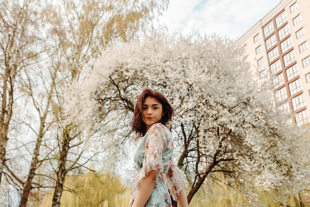 Portrait of charming woman posing near apple cherry tree blossoms blooming flowers in the garden