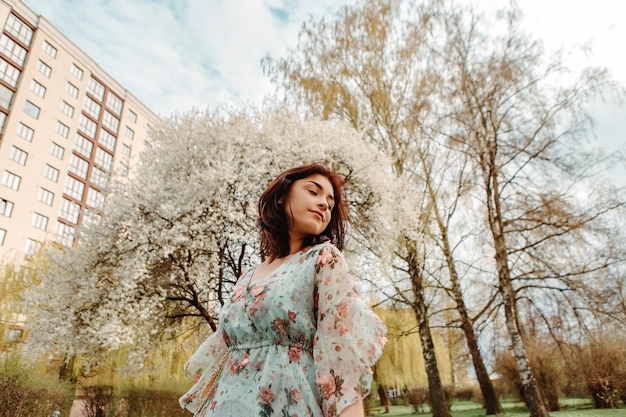 Portrait of charming woman posing near apple cherry tree blossoms blooming flowers in the garden