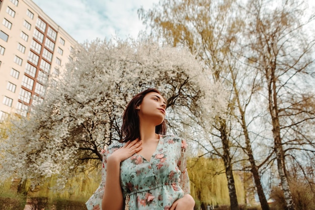 Portrait of charming woman posing near apple cherry tree blossoms blooming flowers in the garden