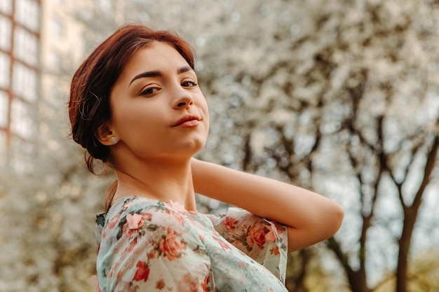 Portrait of charming woman posing near apple cherry tree blossoms blooming flowers in the garden