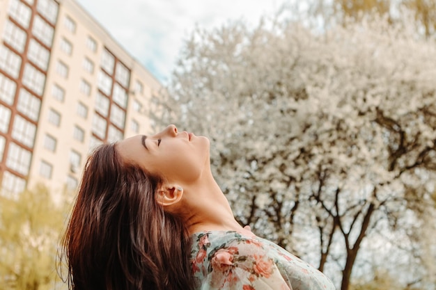 Portrait of charming woman posing near apple cherry tree blossoms blooming flowers in the garden