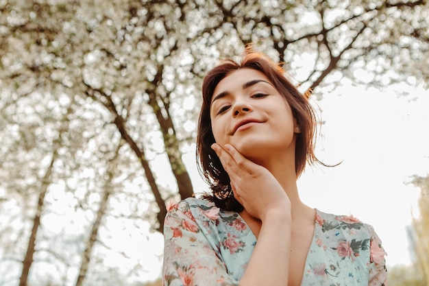 庭に花が咲くリンゴ桜の花の近くでポーズをとる魅力的な女性のポートレート