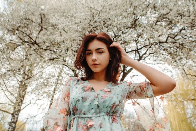 Portrait of charming woman posing near apple cherry tree blossoms blooming flowers in the garden