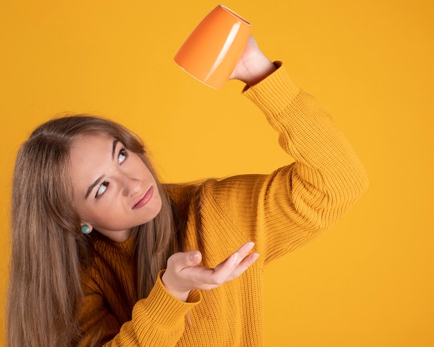 Portrait of charming woman with a cup, on yellow space