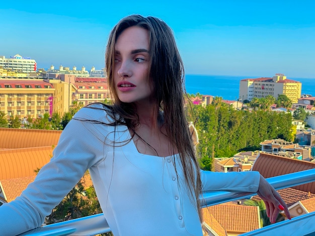 Portrait of charming young girl on balcony looking away with sea view on background