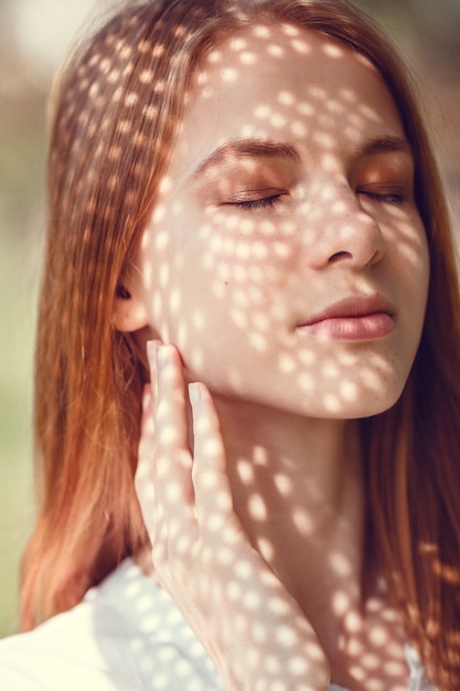 Portrait of a charming young woman outdoor. Light and shadow. interesting portrait of young girl's face covered with unusual shadow