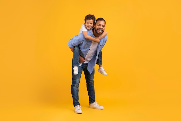 Portrait of cheerful african american dad and little son playing together