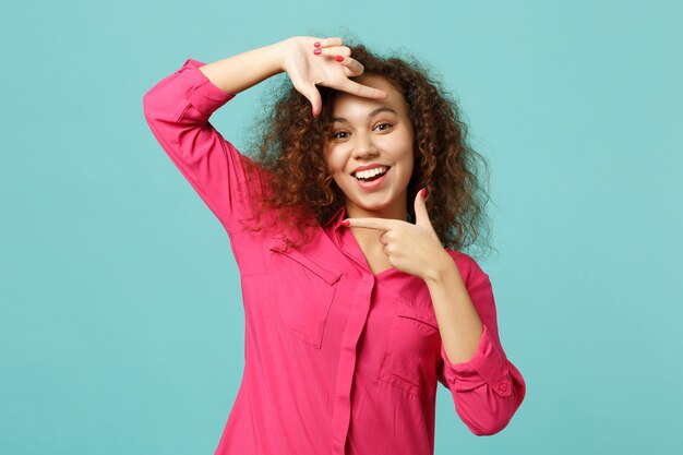 Ritratto di una ragazza africana allegra in abiti casual che fa gesto di cornice per foto con le mani isolato su sfondo turchese blu in studio. concetto di stile di vita di emozioni sincere della gente. mock up copia spazio.