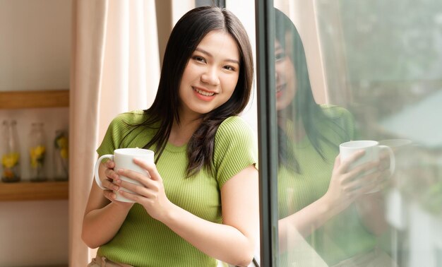 Portrait of a cheerful asian girl in the morning by the window at home