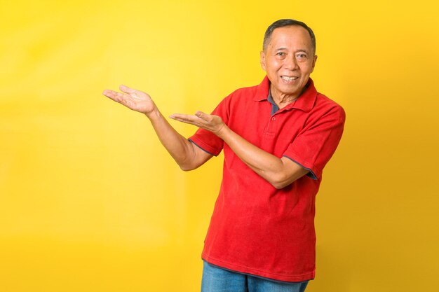 Portrait of cheerful Asian retired old man wears red tshirt pointing hands or presenting