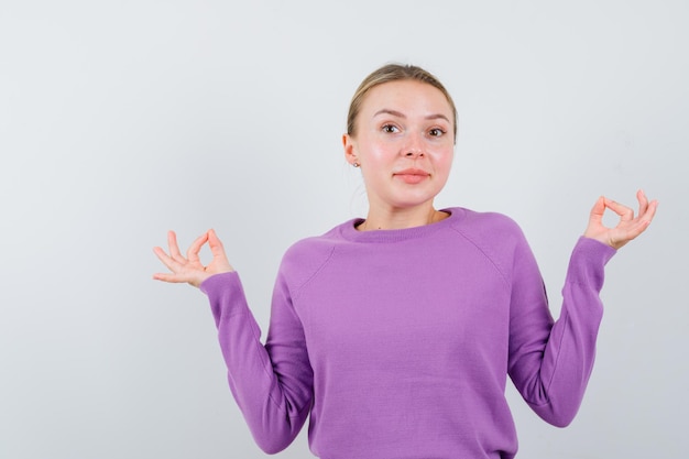 Portrait of Cheerful attractive blonde girl in purple sweater meditate gesture looking great isolated on white background